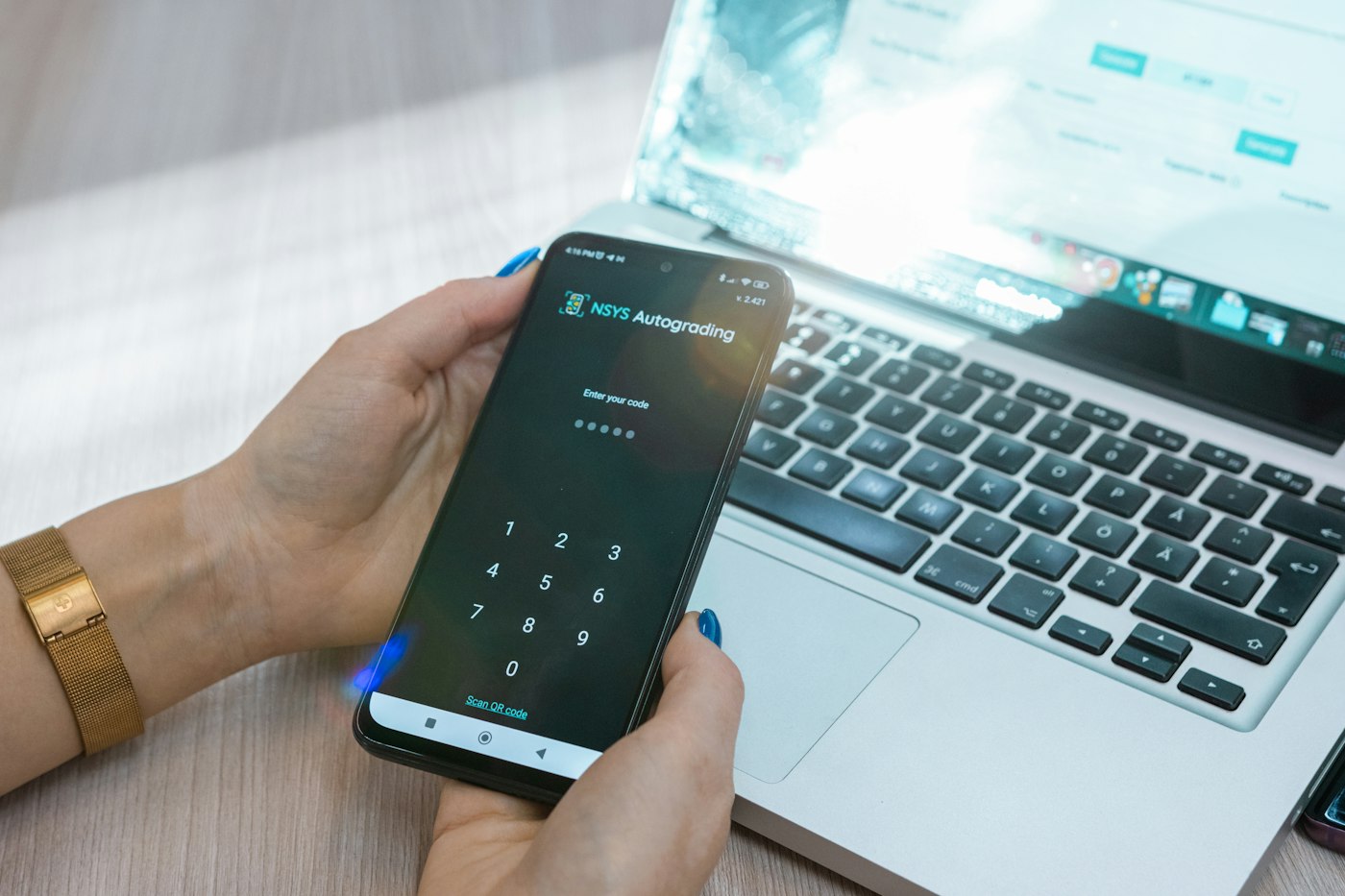 Iemand gebruikt een telefoon, met een laptop op de achtergrond